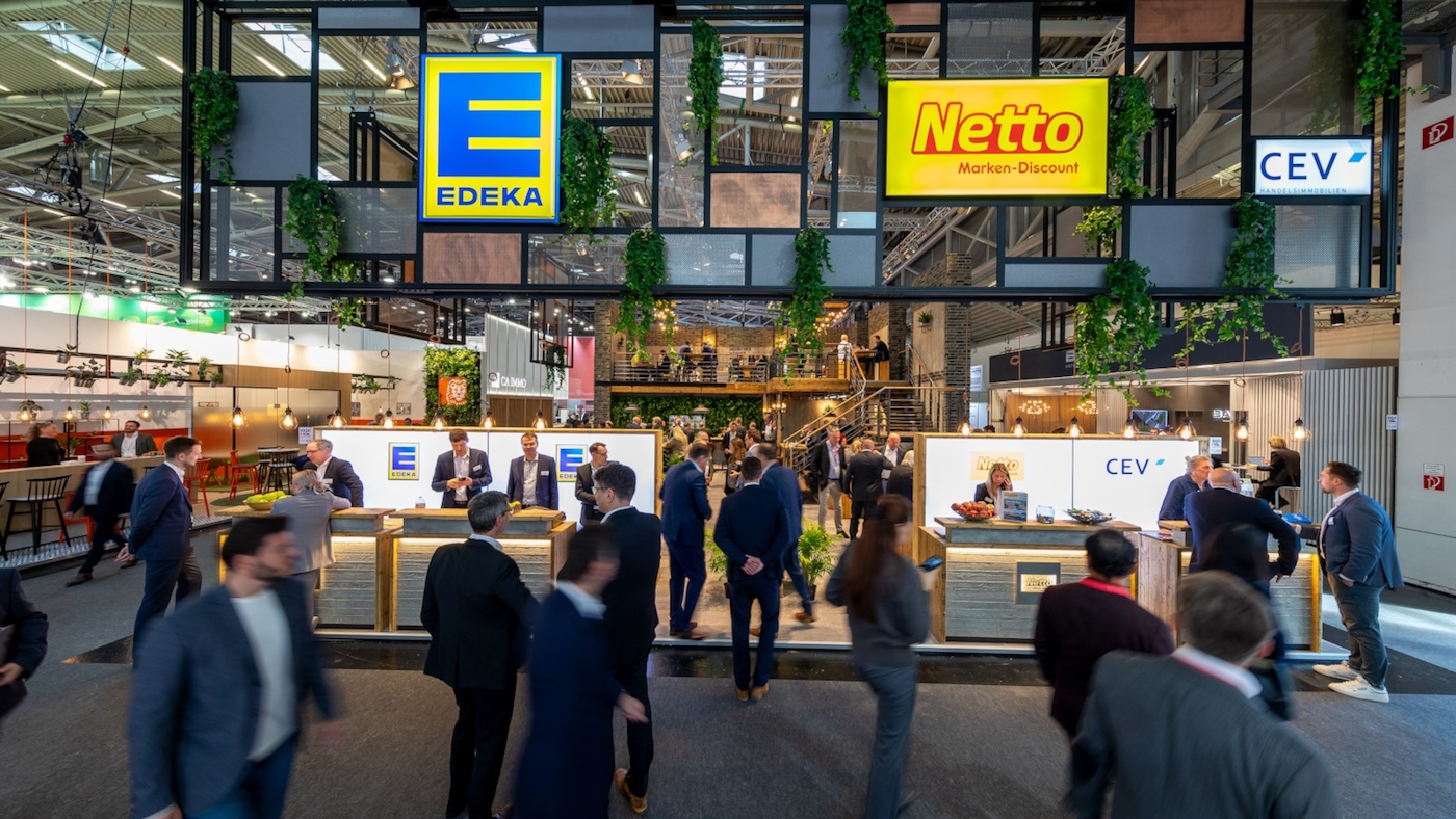 Messestand der EDEKA und Netto on einer Messehalle. Mitarbeitende stehen hinter einer Theke, Besucher laufen im vorbei.